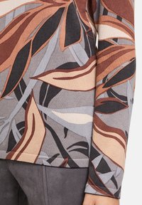 Trui met lange mouwen met een botanisch patroon in tinten bruin, grijs en crème. De stof lijkt een textuur te hebben met geribbelde manchetten.