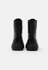 Botins de tornozelo em pele preta com textura de crocodilo, sola de borracha robusta e design sem costuras. Altos com um acabamento mate suave.