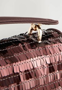 Braune Handtasche mit Pailletten und goldenen Beschlägen, mit einem strukturierten Design und einem glatten Griff, verziert mit gemusterten Pailletten, die in Reihen angeordnet sind.