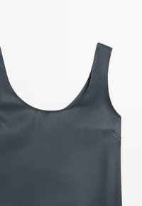 Donkergrijze zijden cami met brede bandjes, ronde halslijn en een gladde textuur. Beschikt over een subtiele zijzak.