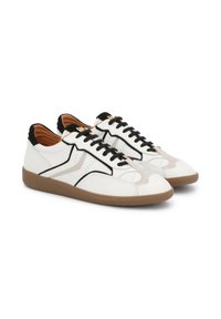 White leather sneakers with black accents, textured gum sole, and contrasting beige suede panel. Features black laces and cushioned interior.