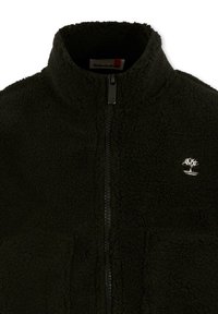 Giacca in pile nera con zip frontale completa e un piccolo logo di albero ricamato in bianco sul petto sinistro.