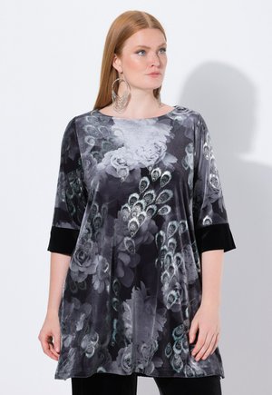 Loose-fitting tunic with a black and grey floral print featuring peacock feathers. Made of soft fabric, with three-quarter sleeves and a rounded neckline.