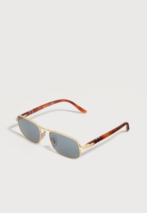 Occhiali da sole rettangolari con montatura in metallo dorato, lenti sfumate blu e aste marroni effetto tartaruga su sfondo bianco.