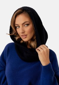 Czarna, dziana kaptur przymocowany do niebieskiego swetra, z prążkowaną fakturą i szerokimi rękawami. Odzież ma luźny krój i miękką tkaninę.