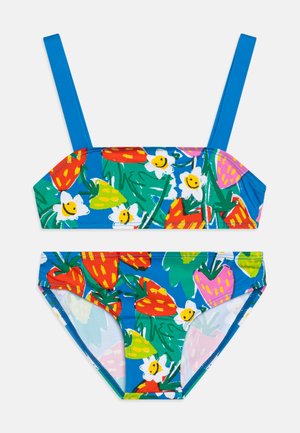 Bikini u dva dijela s jarkoplavom pozadinom koja prikazuje uzorak voća i cvijeća. Gornji dio ima tanke plave naramenice, a donji dio je sličnog uzorka.
