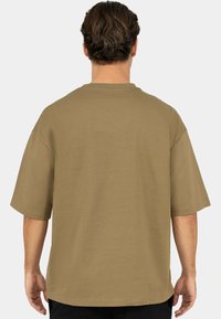 Losse, korte mouwen T-shirt in olijfgroen katoen, met een ronde hals en een effen textuur met gestikte zomen, bekeken vanaf de achterkant.