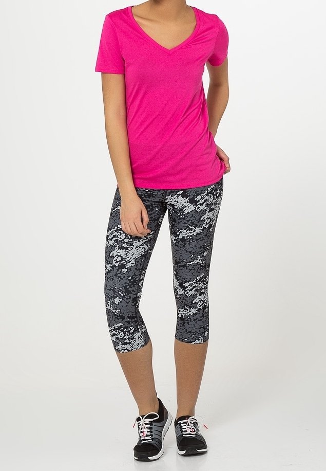 Rosa t-shirt med v-ringning och korta ärmar, tillsammans med svarta och grå mönstrade capribyxor. Svarta träningsskor med vita detaljer.