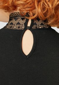 Schwarzes, geripptes Oberteil mit einem Spitzen-Einsatz und ovalem Ausschnitt sowie einem Knopfverschluss am Nacken. Strukturierte, körperbetonte Passform.