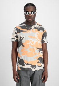 Krátký rukáv camo tričko s oranžovými, šedými a černými vzory, vyrobené z lehkého materiálu s kulatým výstřihem.