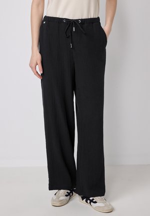 Schwarze, leichte, weite Hosen aus strukturiertem Stoff. Sie verfügen über einen elastischen Bund mit Kordelzug und seitlichen Taschen.