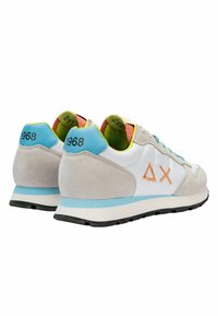 Scarpe sportive con una tomaia in pelle bianca, dettagli in camoscio grigio, rifiniture in blu e giallo neon, e una suola in gomma nera. Presentano un design numerico.