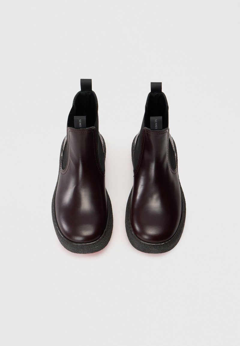Stivali Chelsea in pelle bordeaux con suola in gomma nera texturizzata, dotati di pannelli laterali elastici e linguette posteriori per facilitare la calzata.