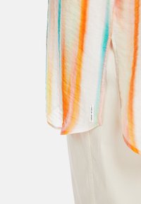 Leichter, transparenter Oberteil mit mehrfarbigen vertikalen Streifen in Orange, Blau, Grün und Pink. Verfügt über einen seitlichen Schlitz und ein Markenlabel.