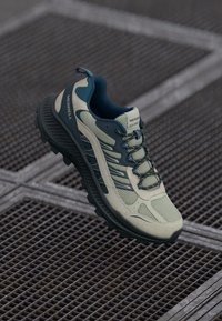 Jasnozielone i granatowe buty trekkingowe z siateczkową górą, wyściełanym kołnierzem, gumową podeszwą i sznurowadłami; zawierają teksturowane akcenty i szczegóły wentylacyjne.