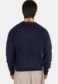 Maglione a coste blu navy con scollatura a girocollo, spalle scese e vestibilità rilassata. Tessuto testurizzato con fascia in vita e polsini.