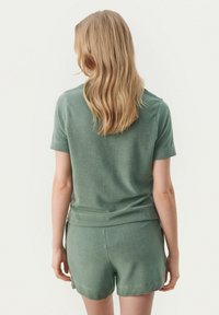 Kortærmet, grøn strikket top parret med matchende shorts, der har et blødt, tekstureret stof og en afslappet pasform.