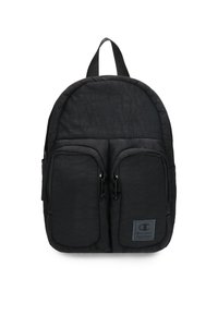 Mochila negra hecha de tela texturizada, de forma redondeada, con dos bolsillos frontales con cremallera y un asa superior para agarrar. Parche con logo en la parte frontal.