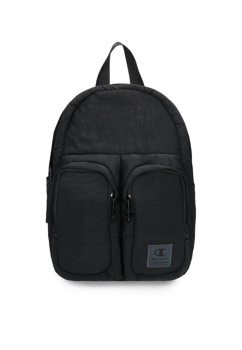 Mochila negra hecha de tela texturizada, de forma redondeada, con dos bolsillos frontales con cremallera y un asa superior para agarrar. Parche con logo en la parte frontal.