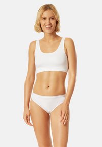 Weißes Baumwoll-Crop-Top und passende Unterhose. Das Crop-Top hat einen Rundhalsausschnitt, und die Unterhose hat einen tiefen Sitz. Glatte Textur.