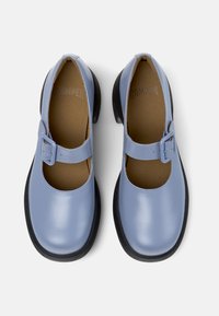 Light blue leather Mary Jane shoes with black thick soles and adjustable buckle straps, viewed from above on a white background.