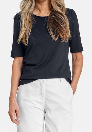 Zwart T-shirt met korte mouwen van zachte katoenen stof, met een ronde halslijn, een losse pasvorm en een gladde textuur. Gecombineerd met witte broek.