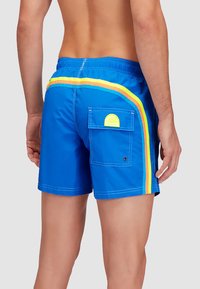 Pantaloni da bagno blu con vita regolabile, tasca laterale e strisce multicolori in giallo neon, arancione e verde sui lati.
