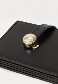 Black leather wallet with a gold snap closure. Features a smooth texture and stitched edges, showcasing a minimalist design.