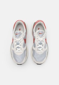 Paire de baskets Nike blanches et grises avec des accents rouges, vues de dessus sur un fond blanc uni.