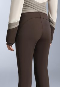 Barna sportos leggings sima textúrával és testhezálló kivitelben. Bordázott részletekkel a felső részen és magasított derékkal a támogatás érdekében.