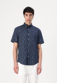 Chemise à manches courtes, boutonnée, en bleu marine avec un motif paisley. Fabriquée en tissu léger, elle dispose d'un col standard et d'une poche poitrine.