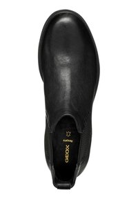 Zapato negro de cuero tipo slip-on con superficie lisa, puntera redondeada, costuras sutiles y acentos elásticos en los laterales. Presenta el logotipo de la marca en el interior.