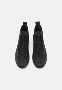 Černé vysoké tenisky s plátěným svrškem, gumovou špičkou a strukturovanými tkaničkami. Mají polstrovaný límec a poutka pro snadné obutí.