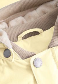 Veste matelassée jaune avec col côtelé beige et doublure en crème douce. Comprend des boutons en argent avec le gravage "MINIATURE". Poignée petite incluse.