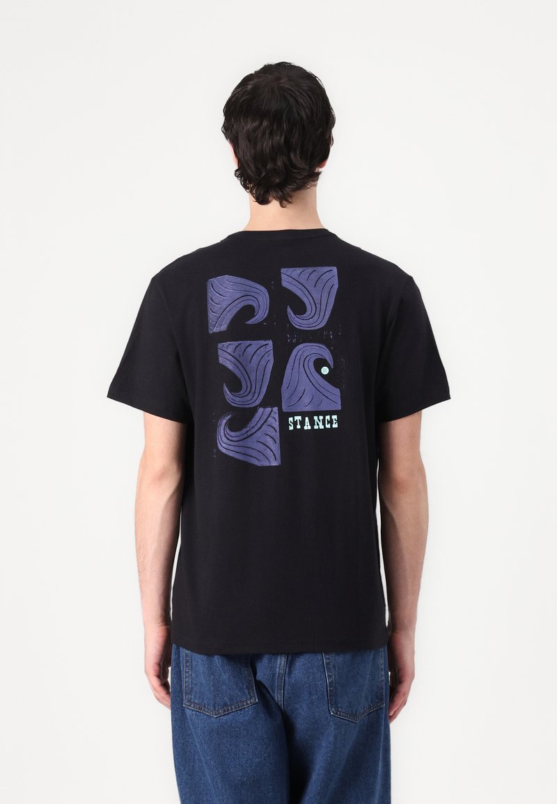 Black cotton t-shirt features a multi-pattern graphic in purple and blue shades, with "STANCE" text at the bottom, relaxed fit, short sleeves.