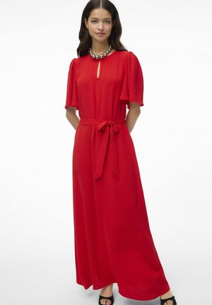 Robe rouge, longueur genou avec de petites manches bouffantes, détail en trou de serrure au niveau du décolleté et ceinture à nouer à la taille. Tissu lisse avec une texture subtile.