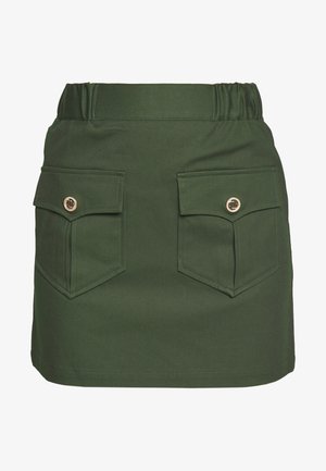 Jupe courte verte avec taille élastique et deux poches à rabat à l'avant, ornées de boutons décoratifs dorés.