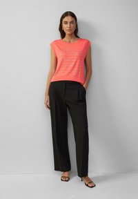 Roze mouwloze top met metallic tekstontwerp, gecombineerd met zwarte wijde broek. Glad materiaal, eenvoudige halslijn en een ontspannen pasvorm.