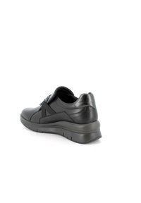 Scarpa sportiva nera con tomaia in pelle liscia, cinturino elastico sulla parte anteriore, punta arrotondata e suola piatta imbottita.