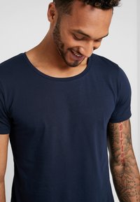 T-shirt in cotone blu navy con scollo rotondo e maniche corte, caratterizzato da una texture liscia e un design aderente.
