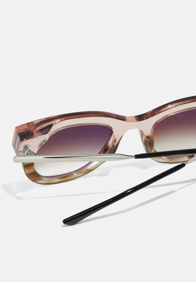 Lunettes de soleil dégradées brunes et roses avec une large monture, accents en métal argenté et une élégante branche noire. Les verres dégradés passent de violet à transparent.