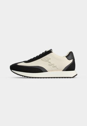Lavprofil sneaker med sorte og off-white paneler, snørelukning foran, rillede såler og kursiv "Boss" logo på siden.