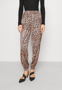 Pantalon imprimé léopard avec une taille élastique, des jambes fuselées et des revers, associé à des chaussures noires à talons. Tissu doux avec une texture lisse.