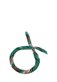 Foulard en soie verte de forme ronde, avec un motif répété de chaînes et d'accents géométriques. Noué pour l'exposition.