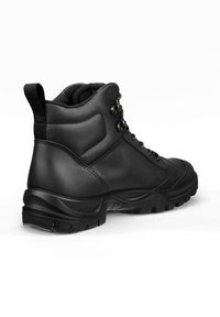 Botín negro hasta el tobillo con un exterior de cuero suave, suela de goma con patrón, diseño de cordones y una lengüeta en el talón para facilitar su uso.