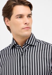 Zwart-wit gestreept shirt met een standaard kraag, knoopsluiting en een gladde textuur; heeft smalle verticale strepen en een klassiek ontwerp.