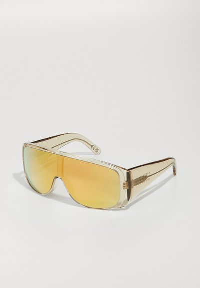Gafas de sol con marco transparente y un diseño de lente ancho, tinte amarillo degradado y detalles en los laterales. Textura suave, forma moderna.