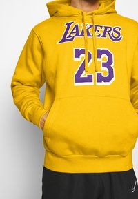 Sweat à capuche jaune avec texte "LAKERS" violet et accents blancs, avec un grand "23" violet. Capuche avec cordon de serrage et poche kangourou à l'avant.