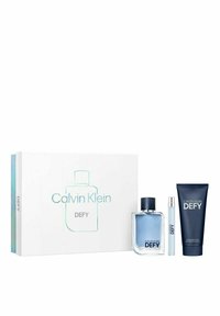 Calvin Klein Defy lahjapaketti sisältää kirkkaan lasipullon, jossa on sinistä nestettä, matkakokoisen suihkepullon ja tummansinisen geelin kroppapesua varten, kaikki avatussa laatikossa.