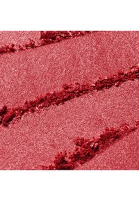 Gros plan de poudre de maquillage rose écrasée scintillante avec des stries texturées à la surface.